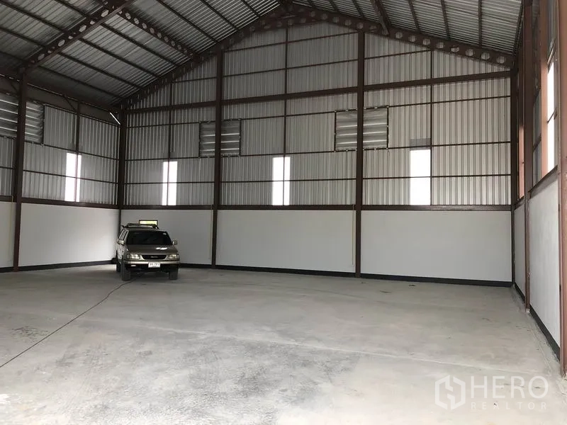 Factory for rent or sale in Sai Noi, Nonthaburi - Large warehouse interior with steel frame walls and ample floor space for vehicles or storage.