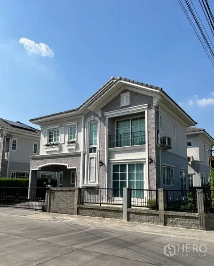 Detached House for rent or sale in Khan Na Yao, Bangkok - Street view of elegant two-storey house with fence, balcony and stone facade.