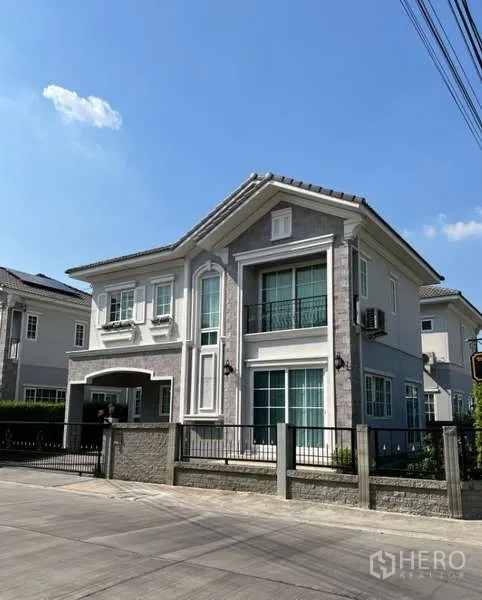 Detached House for rent or sale in Khan Na Yao, Bangkok - Street view of elegant two-storey house with fence, balcony and stone facade.