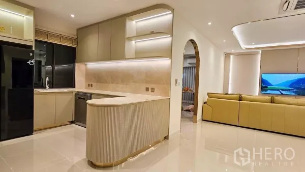 Detached House for rent or sale in Prawet, Bangkok - Open-plan kitchen with curved island, built-in cabinets and ambient lighting flowing into the living area.