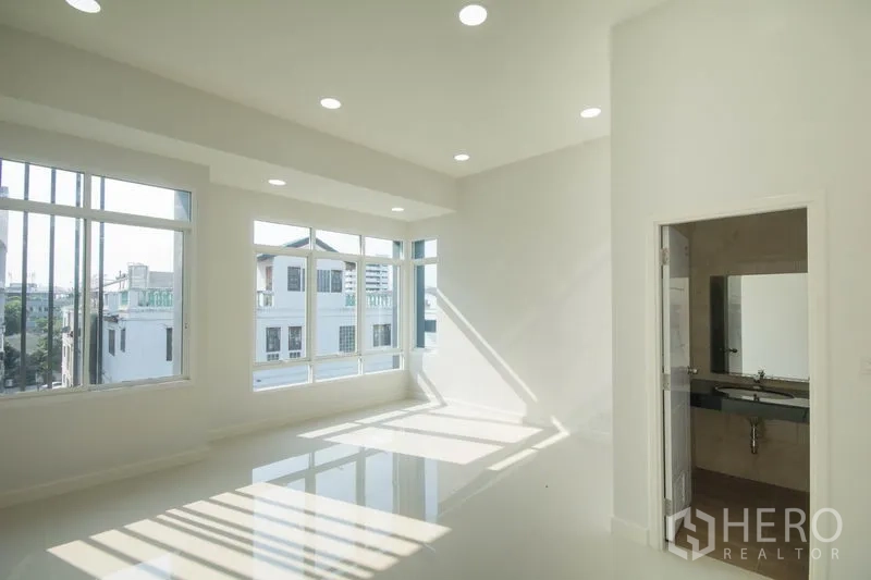 Home Office for sale in Huai Khwang, Bangkok - Corner office level with wraparound windows, recessed lighting and an attached restroom.