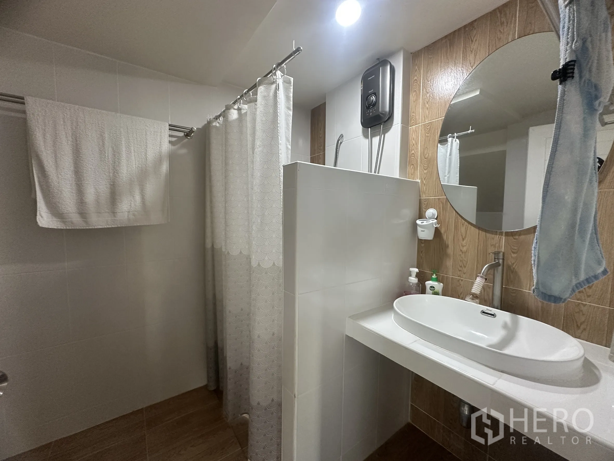 Townhouse for sale in Lam Luk Ka, Pathum Thani - Ground-floor bathroom with shower area, round mirror, and countertop basin.