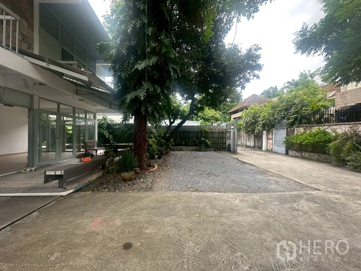 独立式住宅 出租在Watthana, Bangkok - 前院花园有成树、碎石区与车道通向门口。