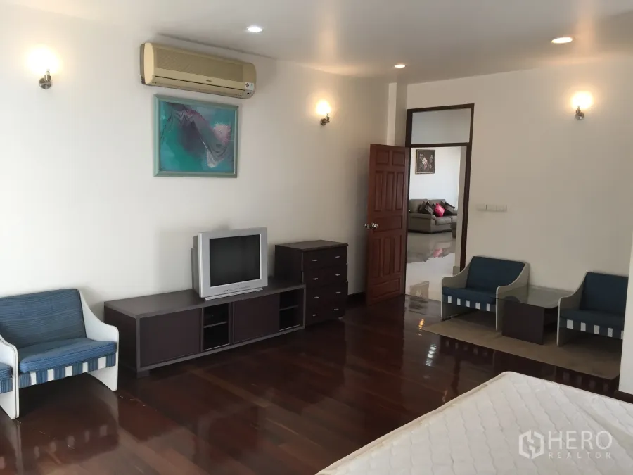 公寓 出租在Watthana, Bangkok - 宽敞卧室，实木地板，壁挂空调，电视柜与休闲座椅。