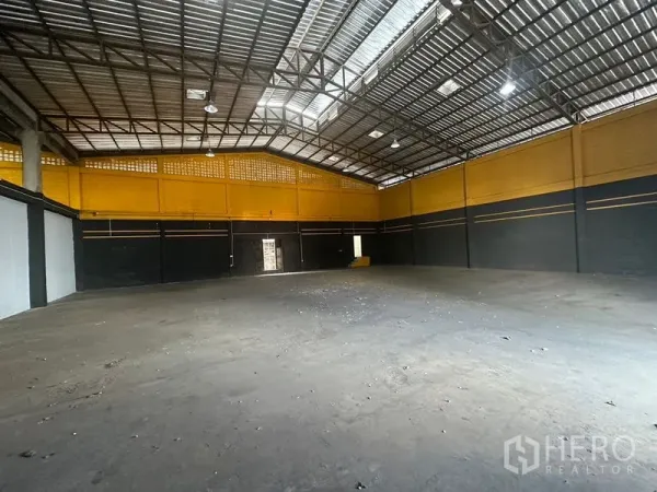 Warehouse for rent in Khlong Toei, Bangkok - Open concrete floor in Bangkok warehouse with yellow-and-black walls and ample lighting.