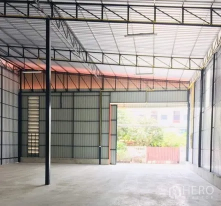 Warehouse for rent in Khan Na Yao, Bangkok - Spacious warehouse interior with high steel truss roof, concrete floor, and wide loading door.