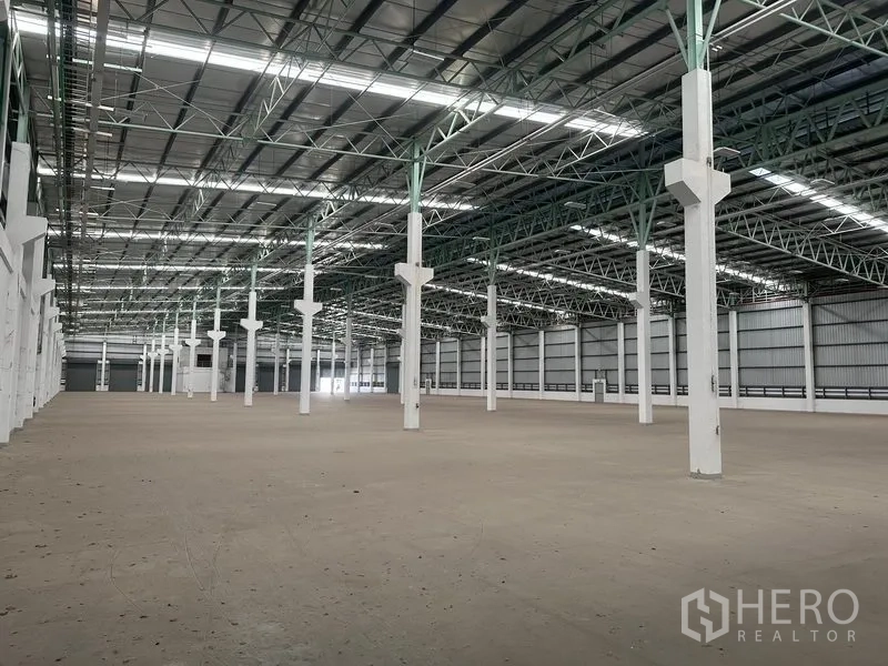 Factory for rent in Bang Sao Thong, Samut Prakan - Angled view of high-clear factory floor with green steel trusses and white columns.