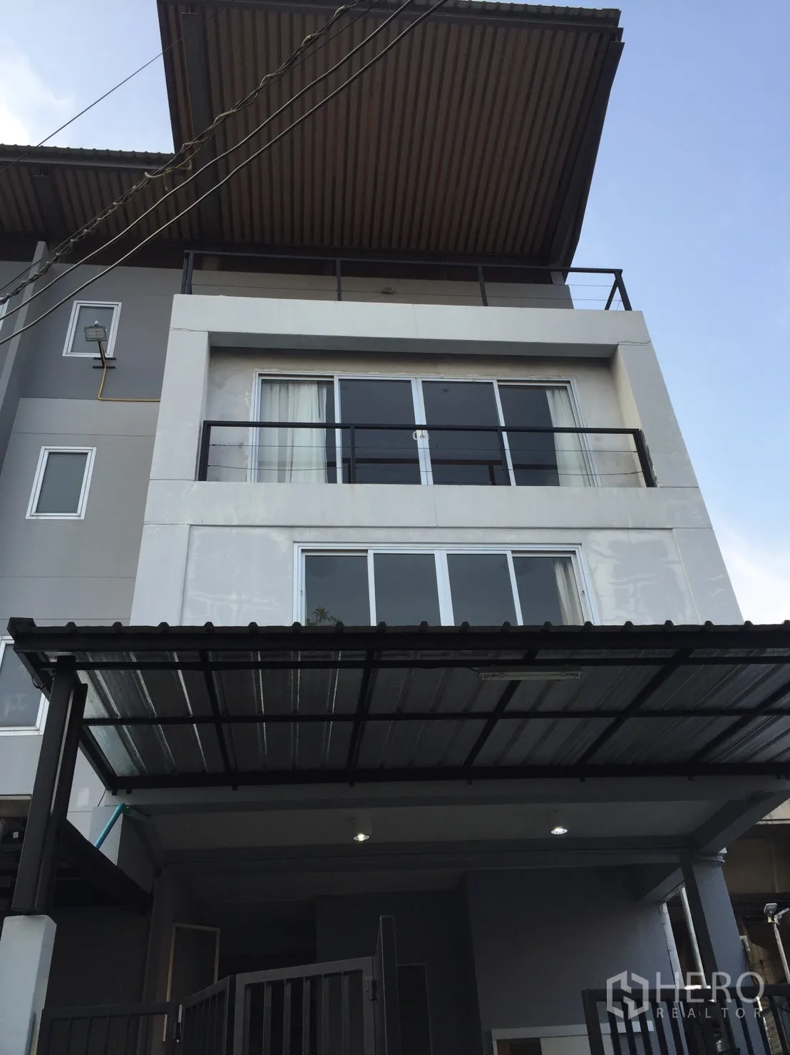 带办公室的家 出租或出售在Suan Luang, Bangkok - 三层住办一体建筑外立面，带阳台与有顶车棚。