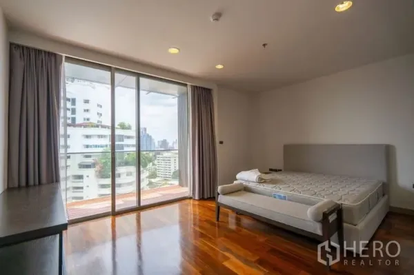 公寓 出租在Khlong Toei, Bangkok - 转角卧室，落地推拉门通向阳台，木地板与城市景色