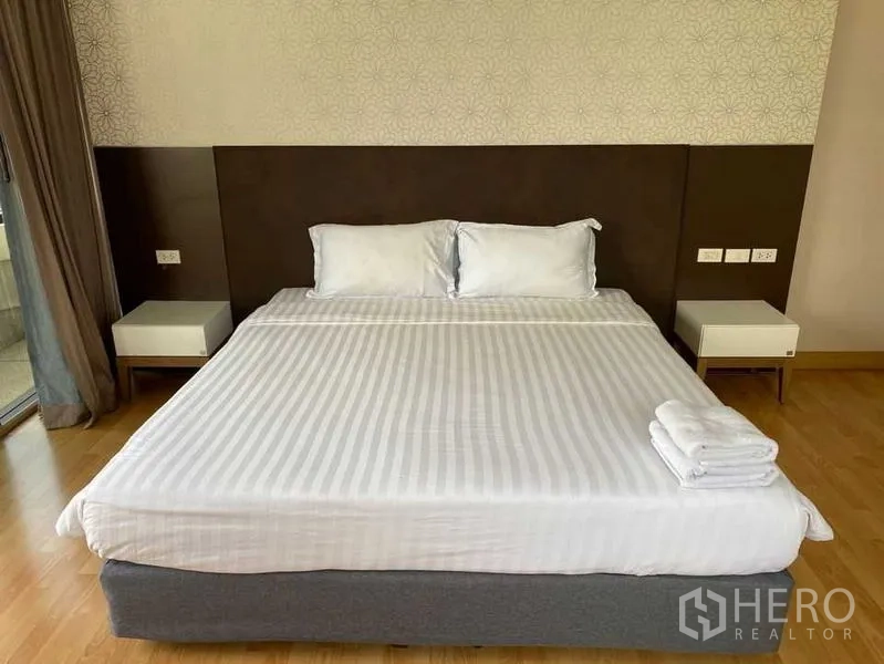 Condominium for rent in Khlong Toei, Bangkok - King-size bed with crisp white linens and a modern headboard.