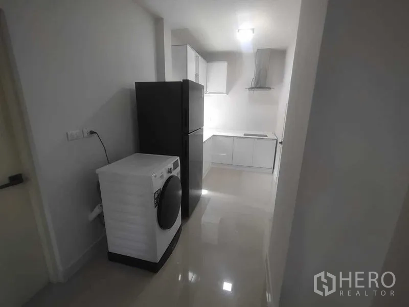 独立式住宅 出租在Khan Na Yao, Bangkok - 厨房过道区配备冰箱和洗衣机，通向烹饪空间。