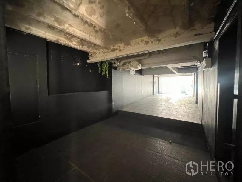Retail Space for rent in Watthana, Bangkok - Open-plan retail interior with tiled ramp, exposed ceiling pipes, and dark feature walls.