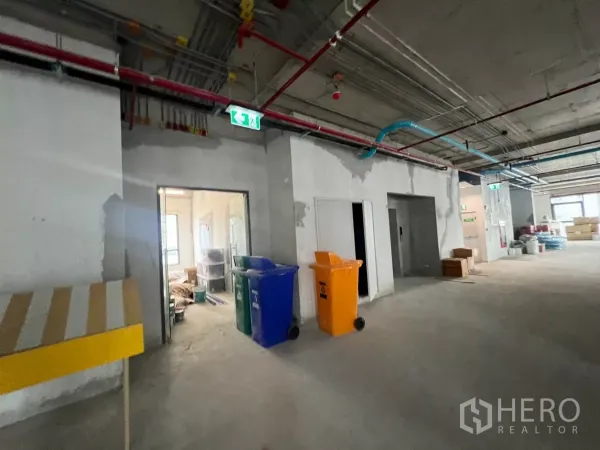 办公空间 出租在Khlong Toei, Bangkok - 办公区走廊，裸露机电管线、紧急出口指示与服务间。