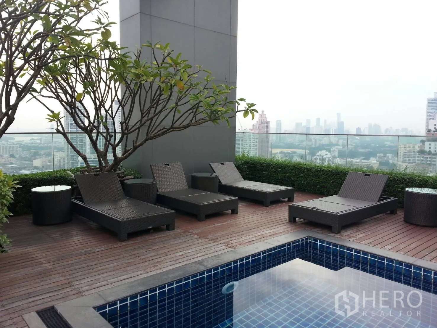 Condominium for rent or sale in Khlong Toei, Bangkok - Rooftop pool deck with sun loungers, greenery and panoramic Bangkok skyline views.