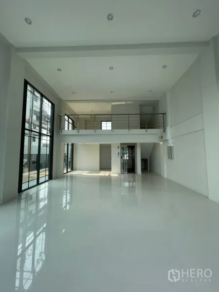 Home Office for rent in Suan Luang, Bangkok - Double-height open lobby with glossy white tiles, floor-to-ceiling windows and a mezzanine railing.