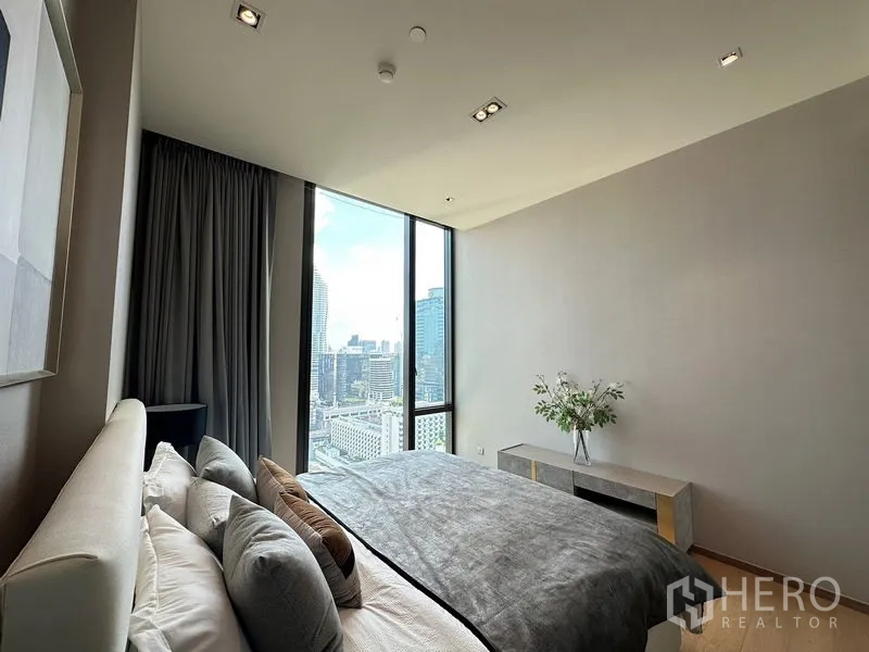 公寓 出租在Pathum Wan, Bangkok - 卧室角度展示高窗框出市中心天际线。