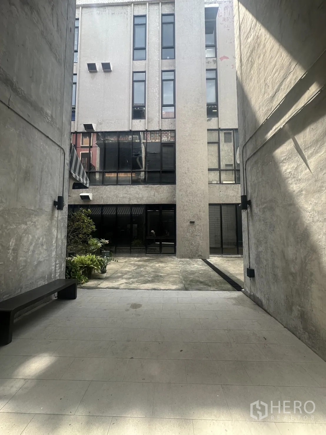 带办公室的家 出租在Pathum Wan, Bangkok - 建筑之间的共享庭院，有长凳、绿植与混凝土步道。