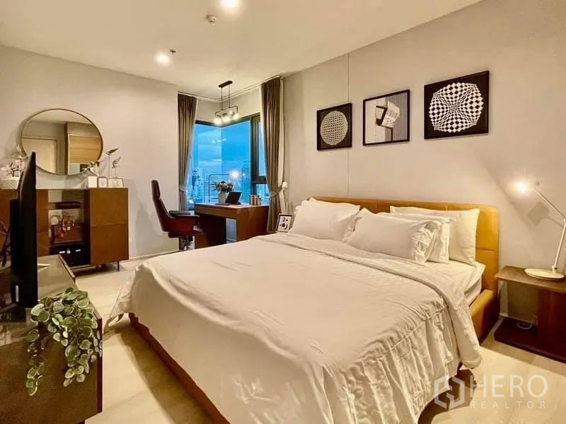 公寓 出租在Pathum Wan, Bangkok - 宽敞主卧，带工作区与暖色灯光，眺望城市。