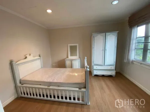Townhouse for rent or sale in Mueang Samut Prakan, Samut Prakan - Bright bedroom with white bed, wardrobe, wood floor and window.