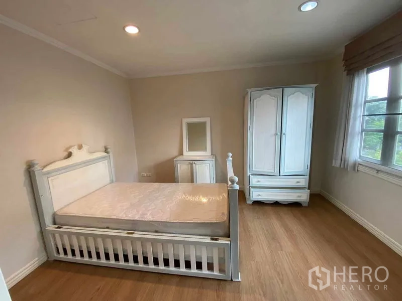 Townhouse for rent or sale in Mueang Samut Prakan, Samut Prakan - Bright bedroom with white bed, wardrobe, wood floor and window.