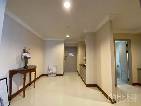 公寓 出租在Watthana, Bangkok - 明亮的入户走廊，摆放玄关桌，浅色墙面并通往卫生间。