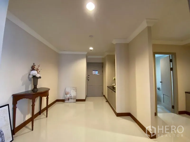公寓 出租在Watthana, Bangkok - 明亮的入户走廊，摆放玄关桌，浅色墙面并通往卫生间。