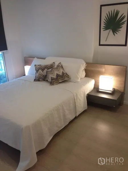 คอนโด ให้เช่าในSathon, Bangkok - ห้องนอนอบอุ่น เตียงคู่ หัวเตียงไม้ และโคมไฟข้างเตียงใน Rhythm Sathorn.
