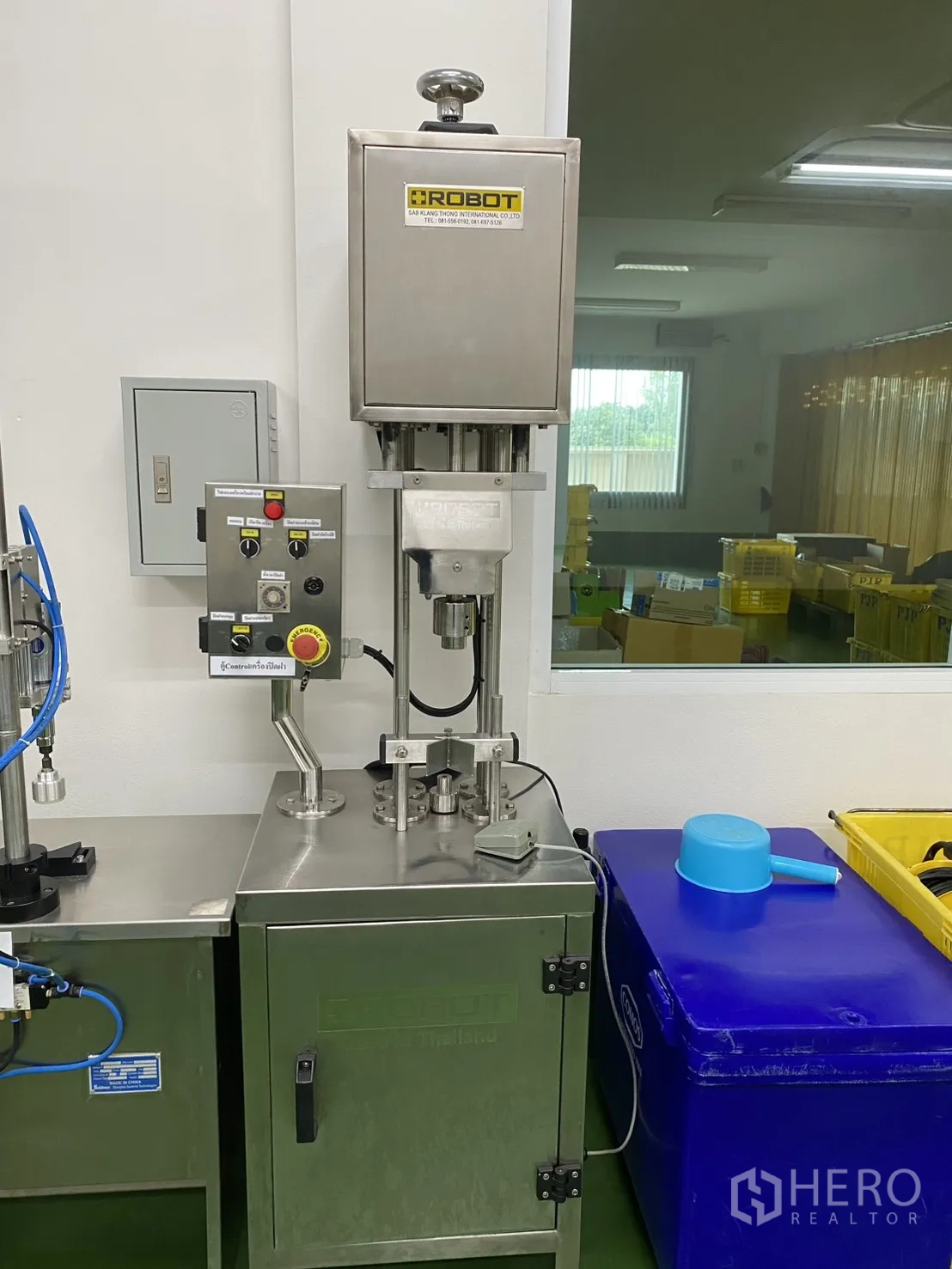 Factory for sale in Khlong Luang, Pathum Thani - Compact sealing machine with control panel inside a white production room.