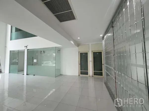 Showroom for rent - Ground-floor lobby with glass partitions, tiled floors, and a roll-up security grille.