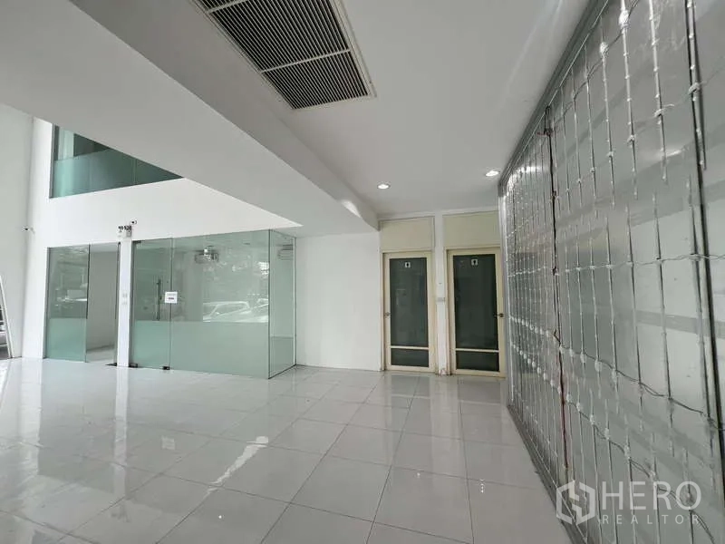 Showroom for rent - Ground-floor lobby with glass partitions, tiled floors, and a roll-up security grille.