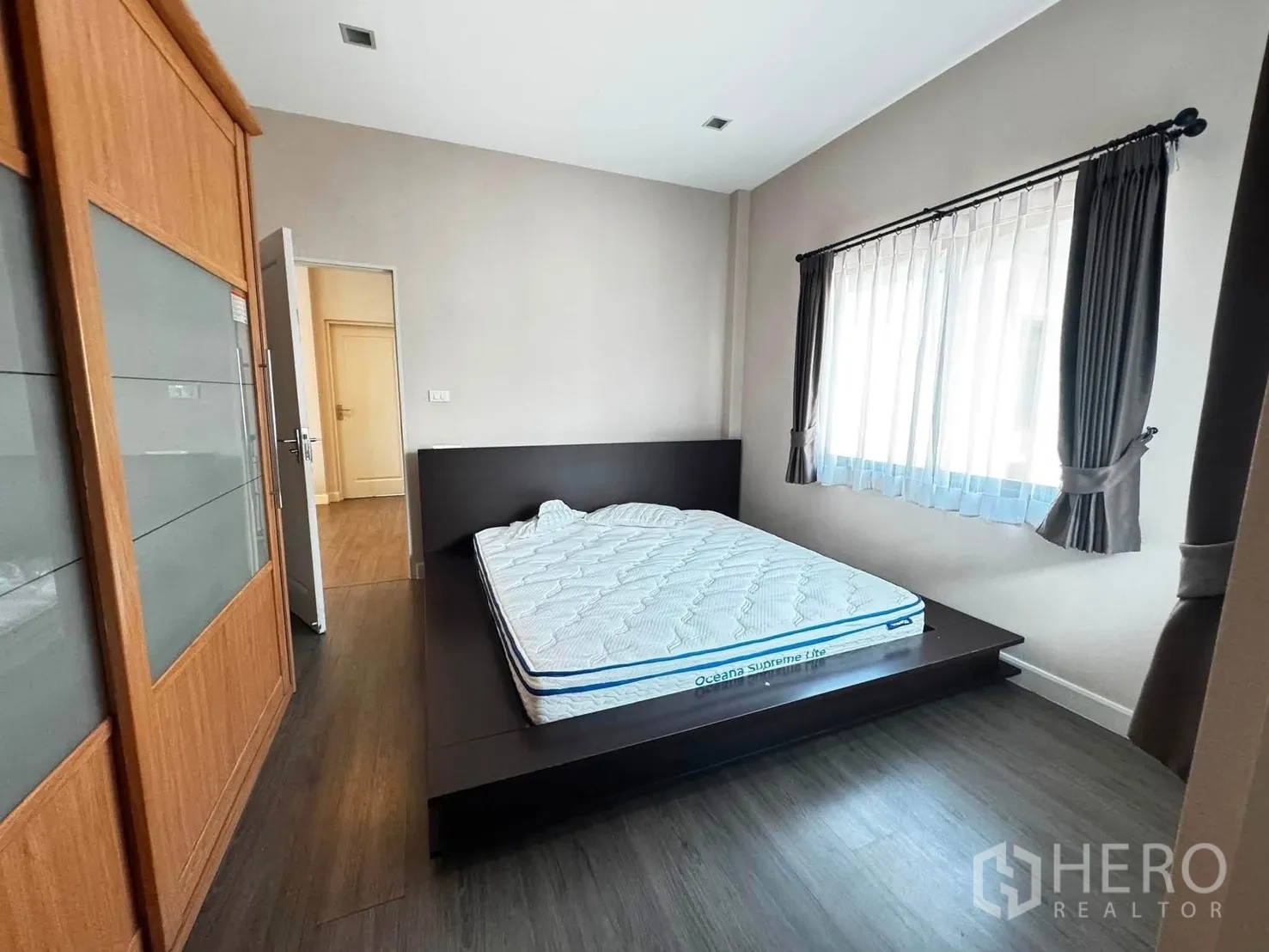 Detached House for rent in Saphan Sung, Bangkok - Bedroom with a platform bed, large wardrobe, and curtained window.