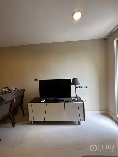 Condominium for rent in Khlong Toei, Bangkok - TV on sleek media console beside dining area near a large window.