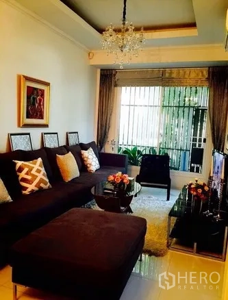 ทาวน์เฮาส์ ให้เช่าในWatthana, Bangkok - ห้องนั่งเล่นอบอุ่น โคมแชนเดอเลียร์ โซฟาตัวแอล ผ้าม่านหน้าต่าง และชั้นวางทีวี