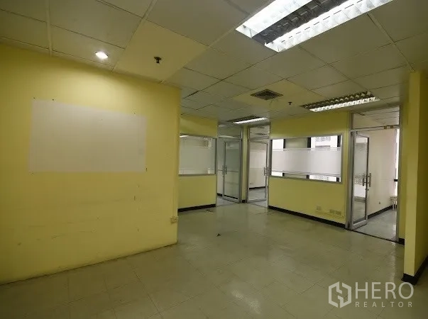 办公空间 出租在Watthana, Bangkok - 开放式区域，设多间玻璃隔断房与浅黄色墙面。