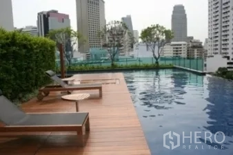 Condominium for rent or sale in Khlong Toei, Bangkok - Rooftop swimming pool with wooden deck, loungers, and city skyline views.