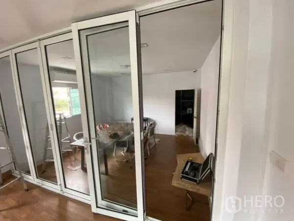 Home Office for sale in Lat Phrao, Bangkok - Glass-partitioned meeting room with sliding doors and wooden flooring.
