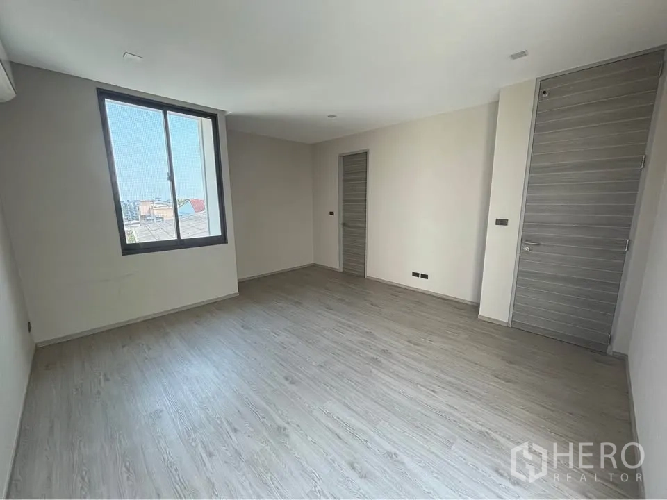 家庭办公室 for rent or sale in Suan Luang, Bangkok - 宽敞房间，大窗与浅色木纹地面。