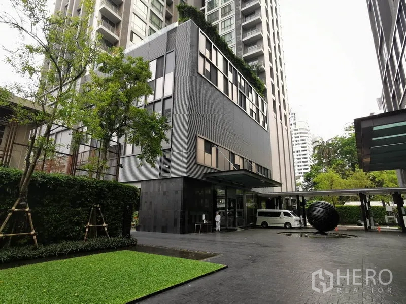 公寓 出租在Watthana, Bangkok - 现代公寓入口，高层外立面、车道与绿化。