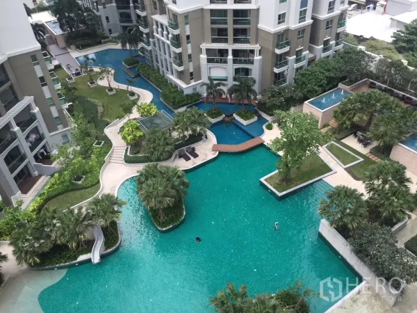 คอนโด ให้เช่าในHuai Khwang, Bangkok - ภาพมุมสูงของสระว่ายน้ำสไตล์ลากูน พื้นที่สวน และสะพานเชื่อม ท่ามกลางอาคารคอนโดโมเดิร์น