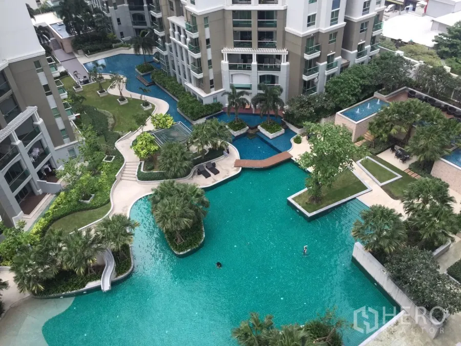 คอนโด ให้เช่าในHuai Khwang, Bangkok - ภาพมุมสูงของสระว่ายน้ำสไตล์ลากูน พื้นที่สวน และสะพานเชื่อม ท่ามกลางอาคารคอนโดโมเดิร์น