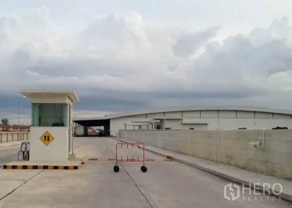 Warehouse for rent in Phra Nakhon Si Ayutthaya - Gated industrial entrance with guard booth and wide truck-friendly concrete road.