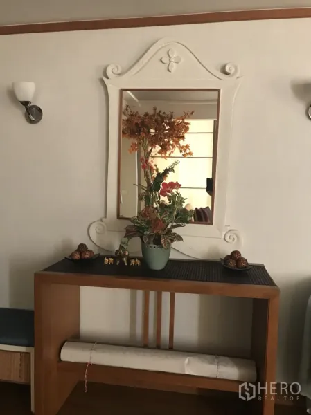 Condominium for rent in Pathum Wan, Bangkok - Entry console with wooden table, ornate framed mirror, and vase of dried flowers in a Bangkok condo.