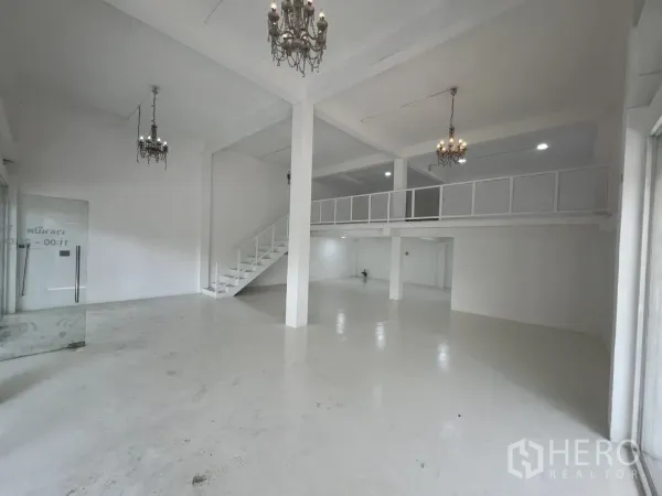 Retail Space for rent in Khlong Toei, Bangkok - Open-plan white retail interior with double-height ceiling, mezzanine and chandeliers.