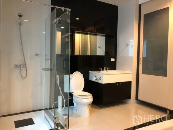 公寓 出租在Pathum Wan, Bangkok - 现代卫浴，玻璃淋浴间、坐便与带镜洗手台。