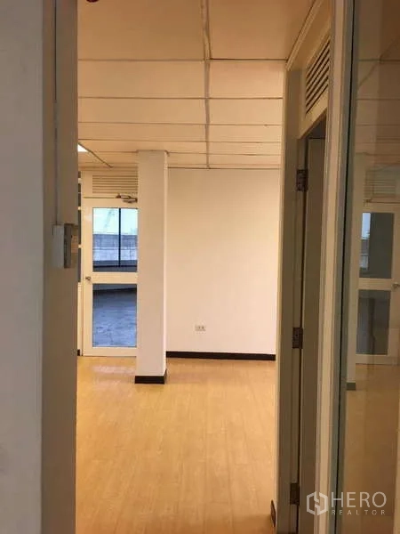 办公空间 出租在Bang Na, Bangkok - 入口走廊通向明亮办公室，木纹地面与玻璃门。