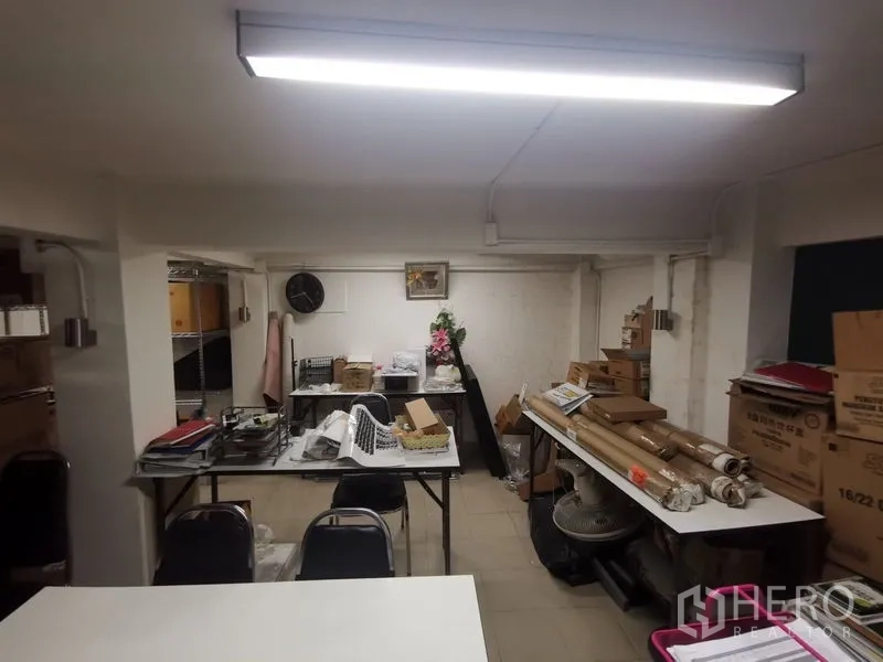 Shophouse for rent in Bangkok - Back office and storage area with tables, packing materials, and fluorescent lights.
