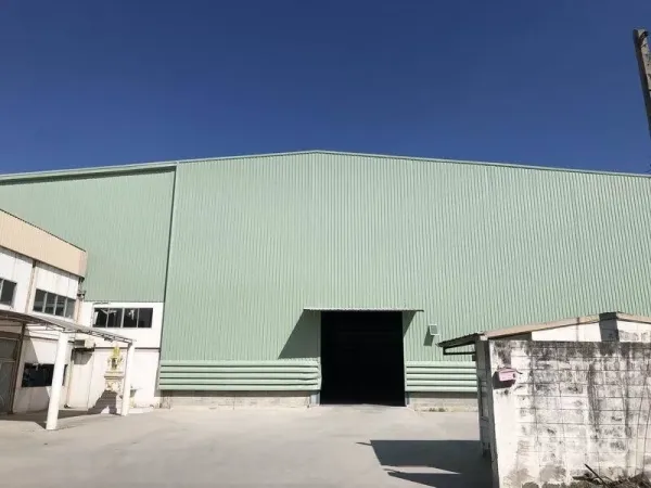 Factory for rent in Bang Phli, Samut Prakan - Front facade of green warehouse with a wide loading door opening to a paved yard.