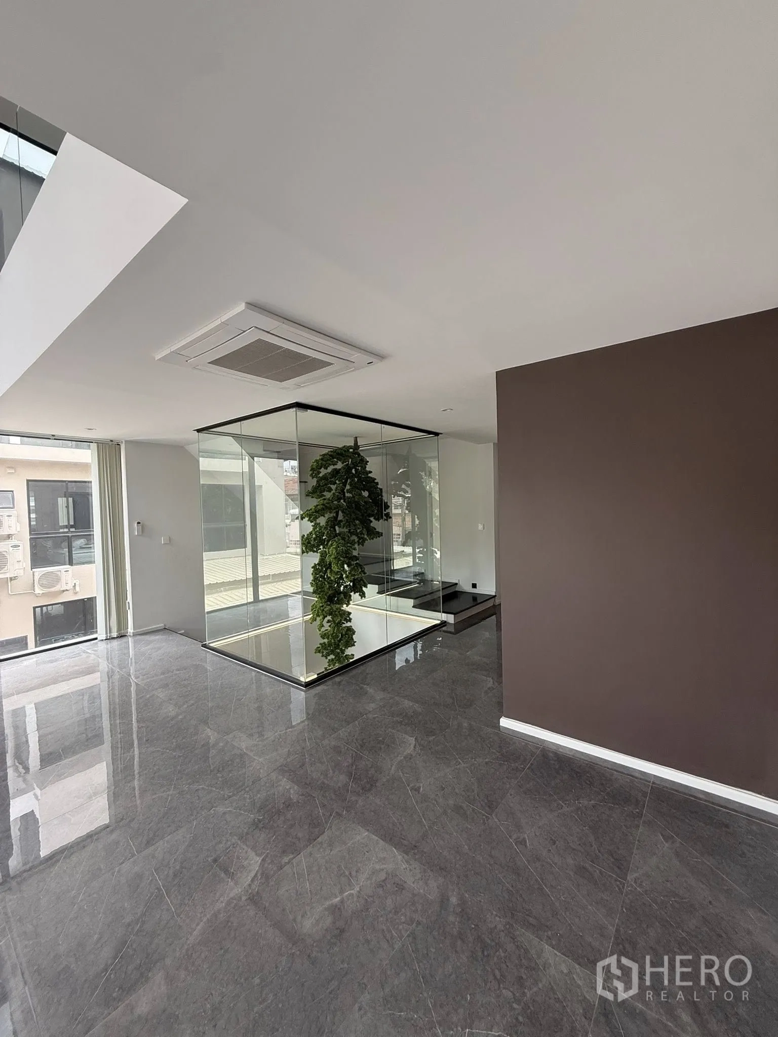 带办公室的家 出租或出售在Lat Phrao, Bangkok - 抛光大理石地面大厅，展示玻璃天井与室内绿景。