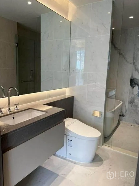 Condominium for rent in Pathum Wan, Bangkok - Vanity with backlit mirror, modern toilet and glass-enclosed wet area.