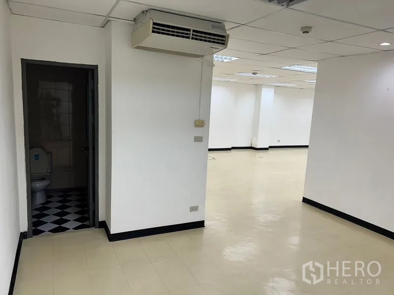 Office Space for rent in Pathum Wan, Bangkok - Office area with wall-mounted air conditioner and entrance to a private restroom off the main workspace.